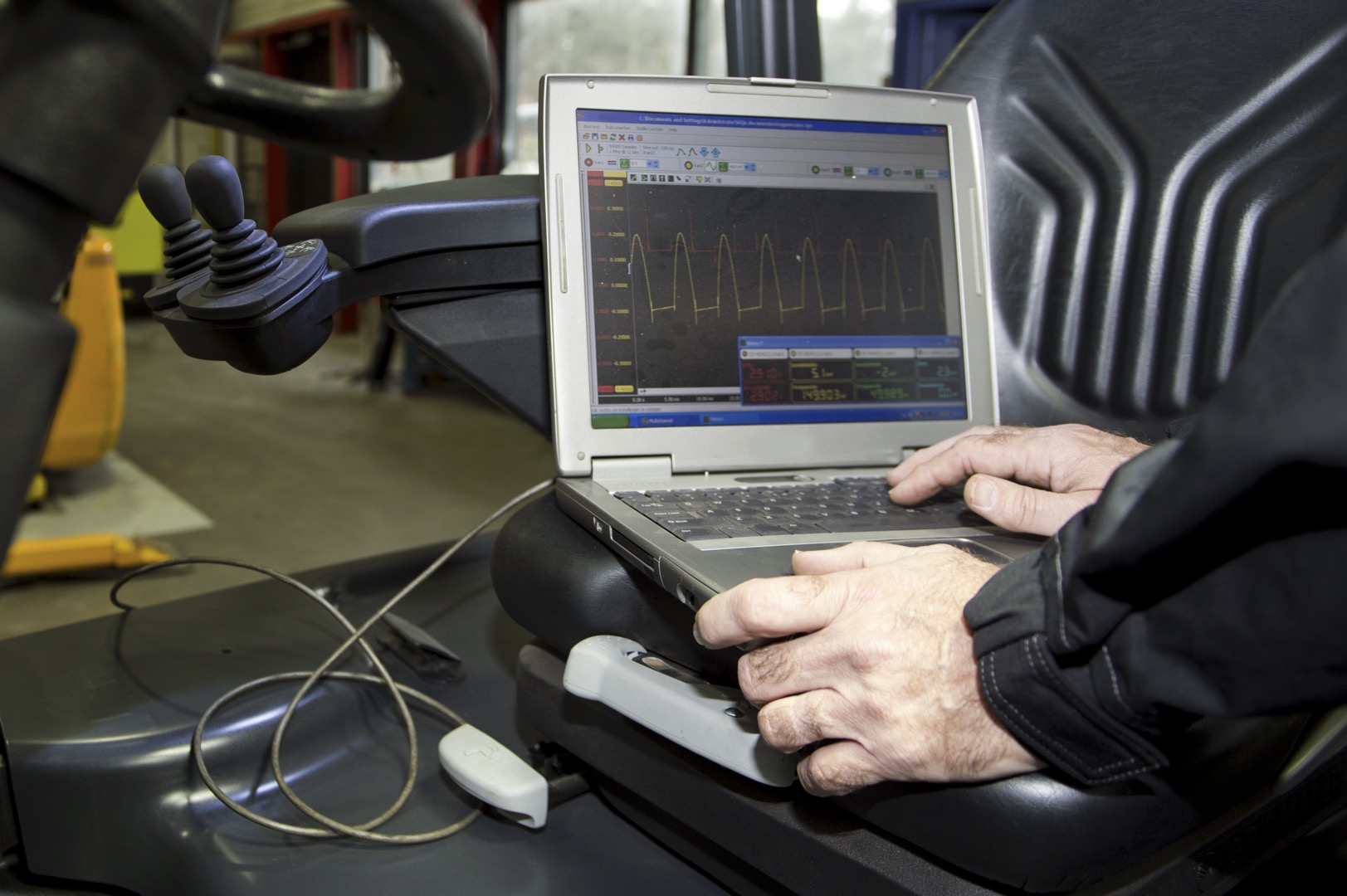 Laptop, hooked up to a forklift's engine and battery, performing various mechatronic checks, outputting the performance in a graph; Shutterstock ID 184121882; purchase_order: -; job: -; client: -; other: -