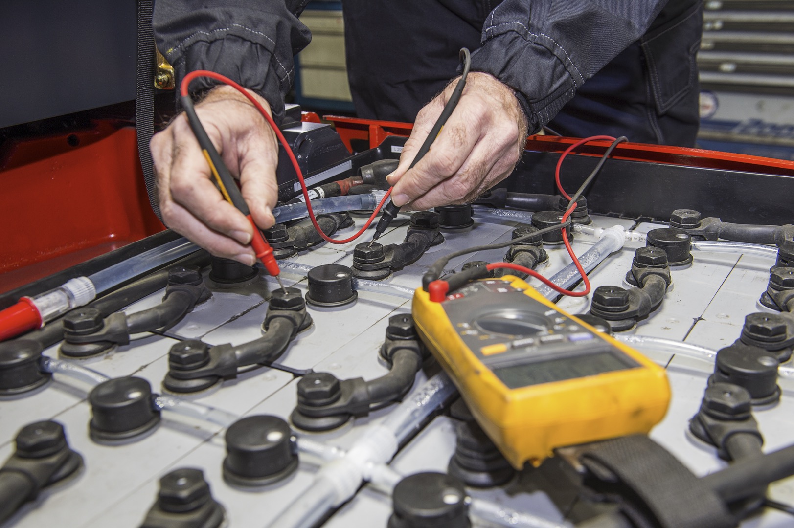 Man, checking the nodes of the battery pack of a forklift, using a multimeter; Shutterstock ID 205500586; purchase_order: -; job: -; client: -; other: -